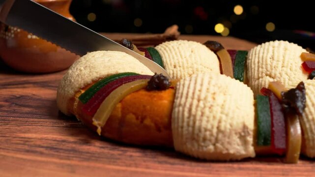 Cutting a slice of rosca de reyes with a knife, close-up view