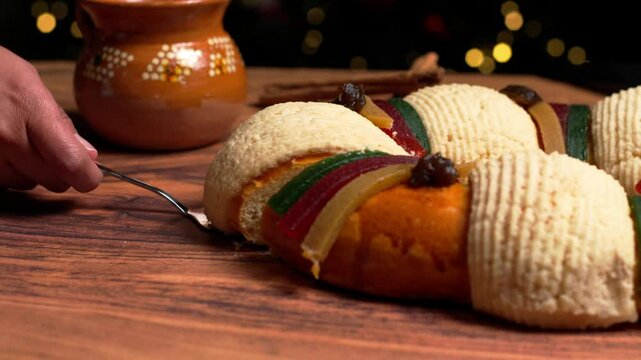 Showing a slice of the traditional rosca de reyes magos or three kings bread with the Christmas tree lights in the background