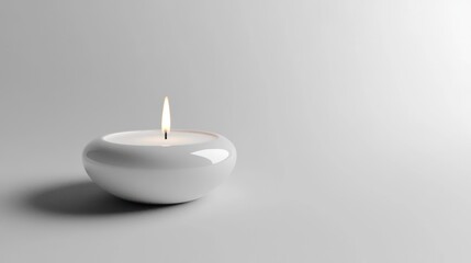 Single white candle burning on plain background.