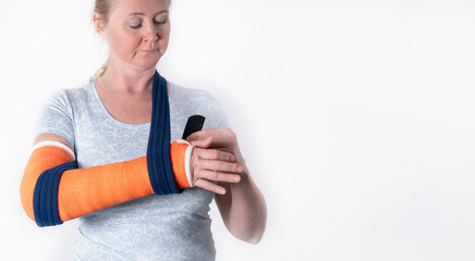 middle aged woman with broken arm in cast hangs her arm in a sling, modern treatment methods, on a...