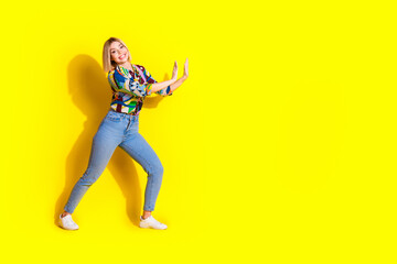 Full body photo of attractive young woman push wall empty space dressed stylish colorful clothes isolated on yellow color background