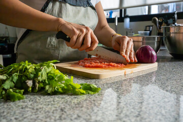 Mujer picando tomate e ingredientes para guacamole