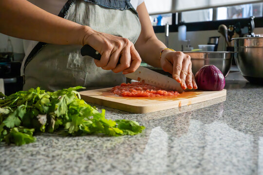 Mujer picando tomate e ingredientes para guacamole