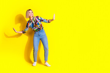 Full length photo of lovely young lady surfing have fun dressed stylish colorful garment isolated on yellow color background