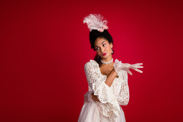 Elegantly dressed woman posing in a white lace gown against deep red background, embodying the blend of baroque and modern fashion
