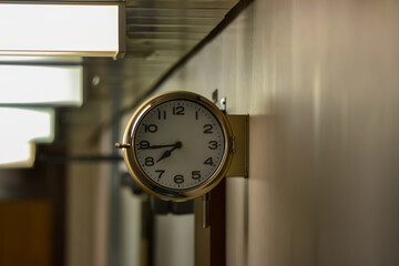 A clock hanging on a wall with the hands at the numbers 7 and 9