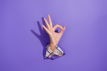 Hand making an OK gesture through a purple background, signifying success and positivity