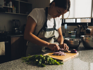 Mujer cortando vegetales para preparar guacamole en la cocina con tabla de picar