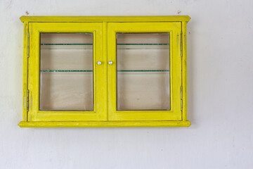 a small old yellow wall shelf with a door