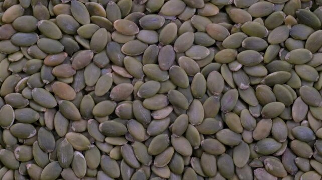Top down view. Stack of green pumpkin seeds without shells. Slider shot. Depth of field, selective focus. Food, nutrition, healthy eating, organic, snacks, ingredient concepts. 4k