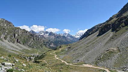 Tranquil mountain pass with winding trails snow capped peaks and blue sky