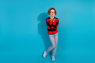 Young woman with curly red hair blowing a kiss against a vibrant blue background