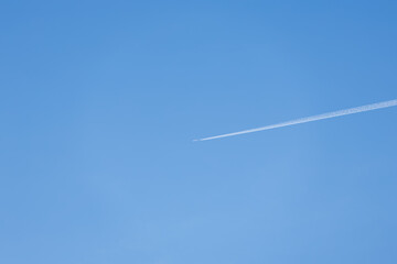 青空を白く長い飛行機雲を作りながら進む旅客機