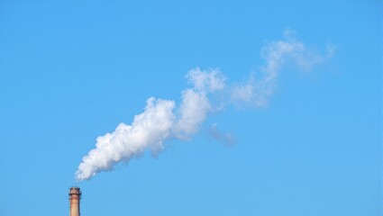 Pollution Chimney emitting smoke against blue sky