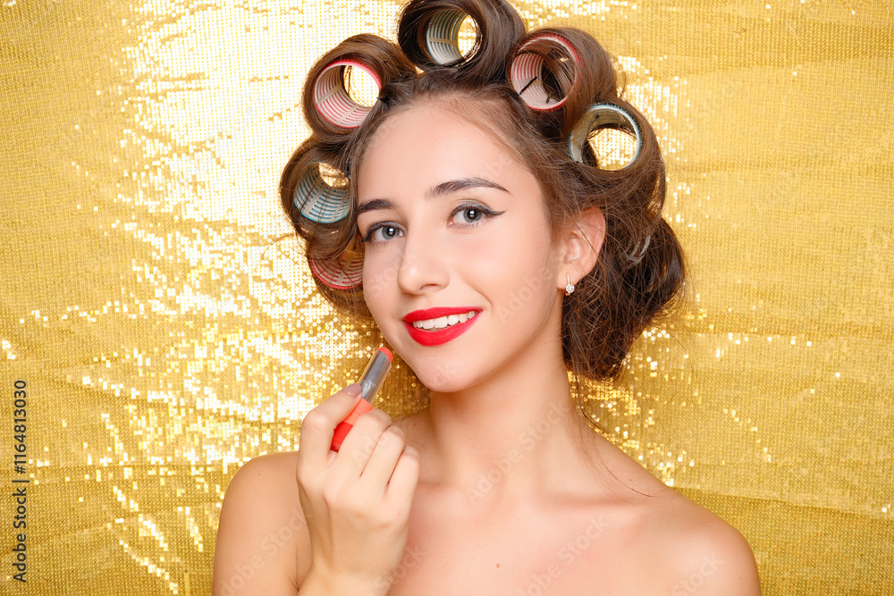 Wall mural Beautiful girl in hair curlers isolated on gold