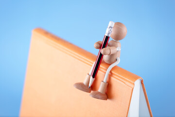 A puppet sitting on a book with a pencil in his hand