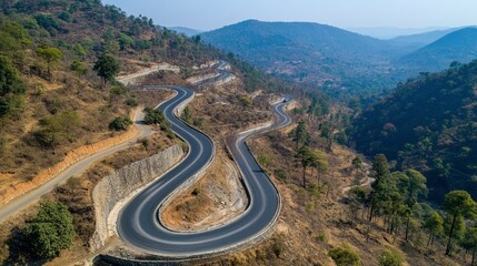 Fototapeta premium Winding Mountain Road Through Lush Green Hills