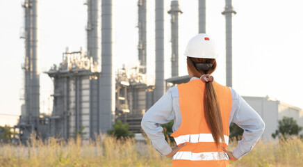 Worker Observes Industrial Power Plant With Tall Smokestacks During Afternoon Daylight in Rural Area