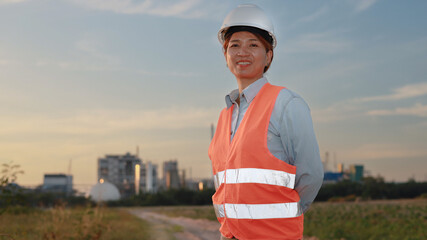 Smiling Construction Worker in Safety Vest Stands Confidently at Sunset in Urban Landscape