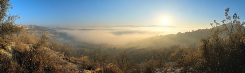 Obraz premium Panoramic sunrise view over misty valley and hills.
