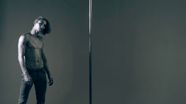Strip dancer. Fit slim muscular man on pole dance. Pole dancer on pylon. Shirtless strong sexy man dancing. Male flexibility, and grace. Guy performing trick on pole. Male athlete doing acrobatic