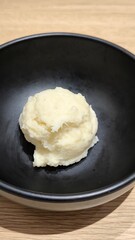 Mashed potatoes in a black cup on a wooden table