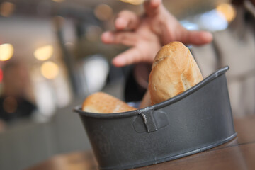 A Hand Reaching for Various Freshly Baked Breads in a Cozy Restaurant