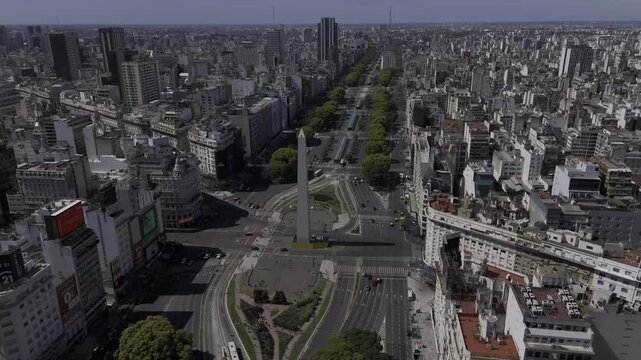 Drone orbits to the right around obelisk in wide shot of Plaza de la Republica in Buenos Aires, Argentina