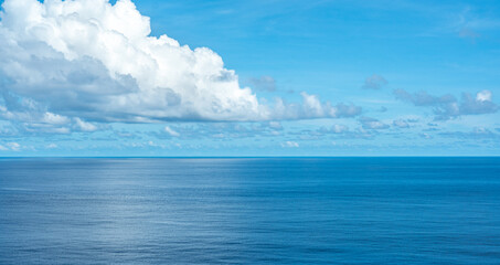 Calm ocean with clear blue sky and fluffy white clouds, serene seascape horizon, tranquil water...