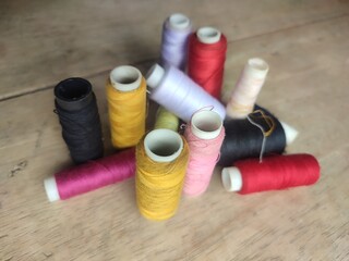 Collection of colorful sewing threads on a wooden base