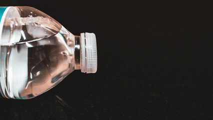 close-up of small plastic water bottle on black background