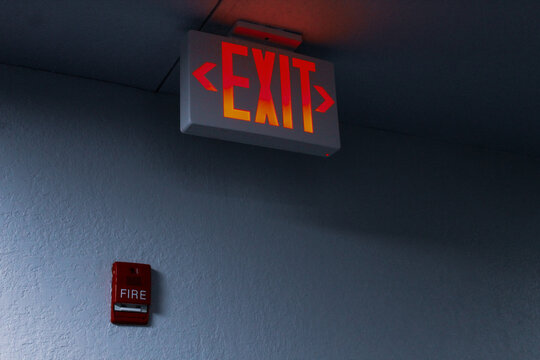 close-up of a large illuminated LED emergency exit sign and fire alarm safety pull installation example