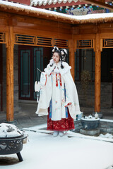 Asian girl wearing Ming Dynasty Hanfu outdoors after heavy snow