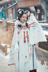 Asian girl wearing Ming Dynasty Hanfu outdoors after heavy snow