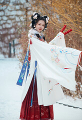 Asian girl wearing Ming Dynasty Hanfu outdoors after heavy snow