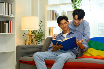 Fototapeta premium Happy male gay couple enjoying quality time together and reading book on couch