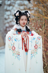 Asian girl wearing Ming Dynasty Hanfu outdoors after heavy snow