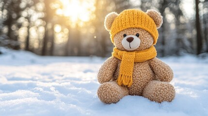 Cozy teddy bear in yellow hat and scarf sits in snow at sunrise