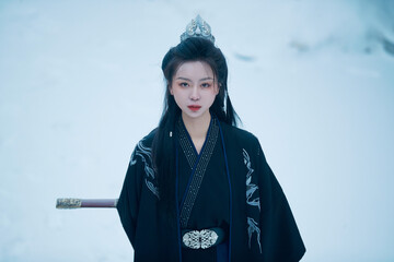 A Chinese girl dressed in Hanfu plays a martial arts hero in the snowy ancient city