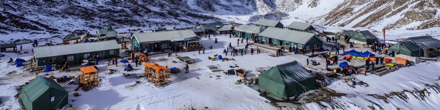 Aerial panorama of trekkers resting at Gorak Shep, with the towering peaks of the Himalayas creating a breathtaking backdrop, in 4K resolution