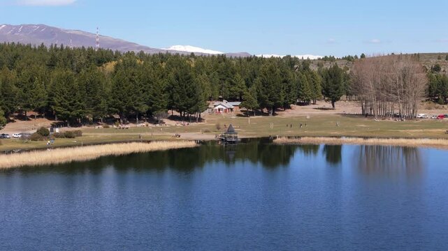 Tourists enjoying sunny day at la zeta lagoon, a beautiful natural reserve near esquel, patagonia, argentina, with the andes mountains reflecting on the calm water surface, drone establishing shot