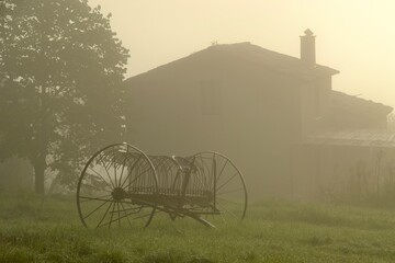 Old farm equipment in misty field in Provence