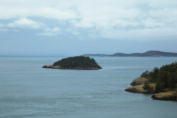 Fototapeta premium Rugged coastal cliffs meet calm ocean waters under soft cloudy blue sky