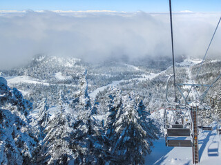 Forest covered with rime and a sea of clouds viewed from a chairlift at the top of ski resort...