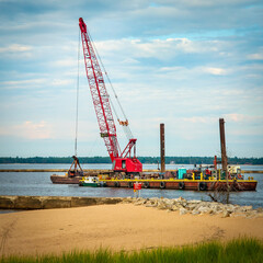 Dredge crane digging and filtering trench in harbor for boats