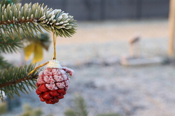 A beautiful frosty pine cone ornament hangs gracefully on a winter tree branch outdoors