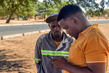african village, two man outdoors using a phone, volunteer at charity organization teaching...