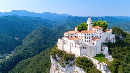 Obraz premium Aerial view of a historic monastery on a cliff surrounded by mountains.