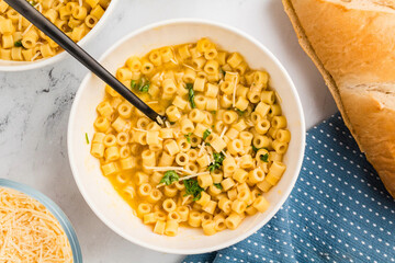 Warm Parmesan pasta soup in a bowl, garnished with parsley