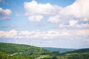 Windmill Renewable Energy Turbines Spinning on a Tree Covered Mountain